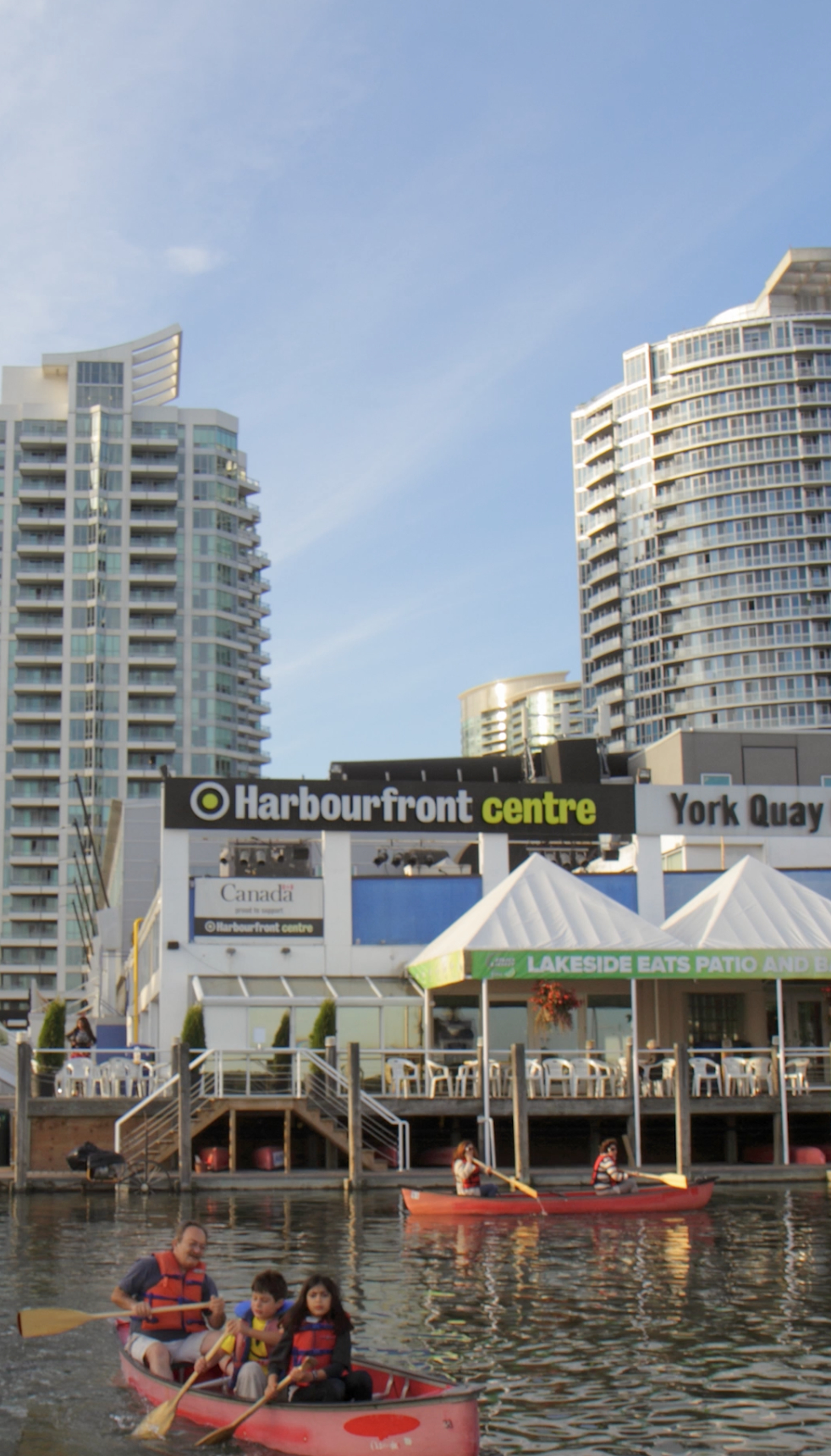 Toronto Harbourfront Centre, behind the lake where groups of people canoe with life jackets on.