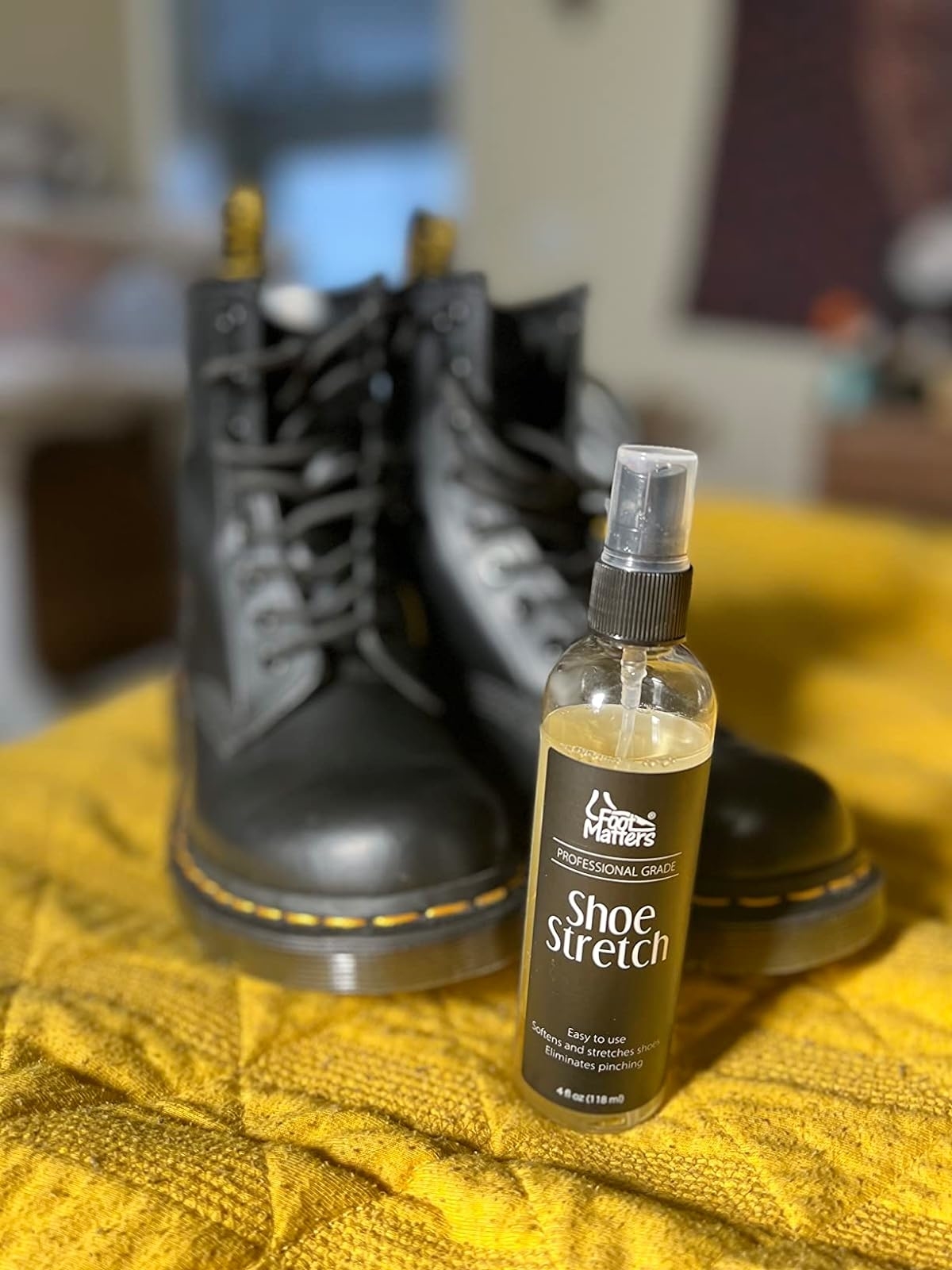 Reviewer&#x27;s photo of a pair of Doc Martens posed with a bottle of the shoe stretch spray
