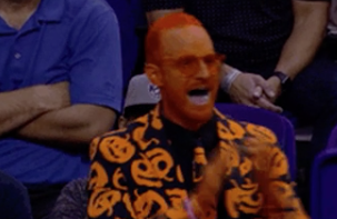 Closeup of a man painted orange and wearing a pumpkin blazer and tie