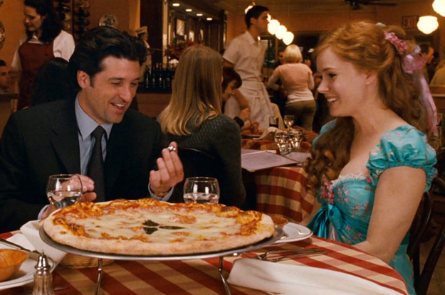 Patrick Dempsey and Amy Adams sitting at a table in front of a cheese pizza as Robert and Giselle in Enchanted