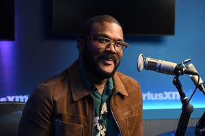 Tyler Perry leans close to a microphone during a radio interview