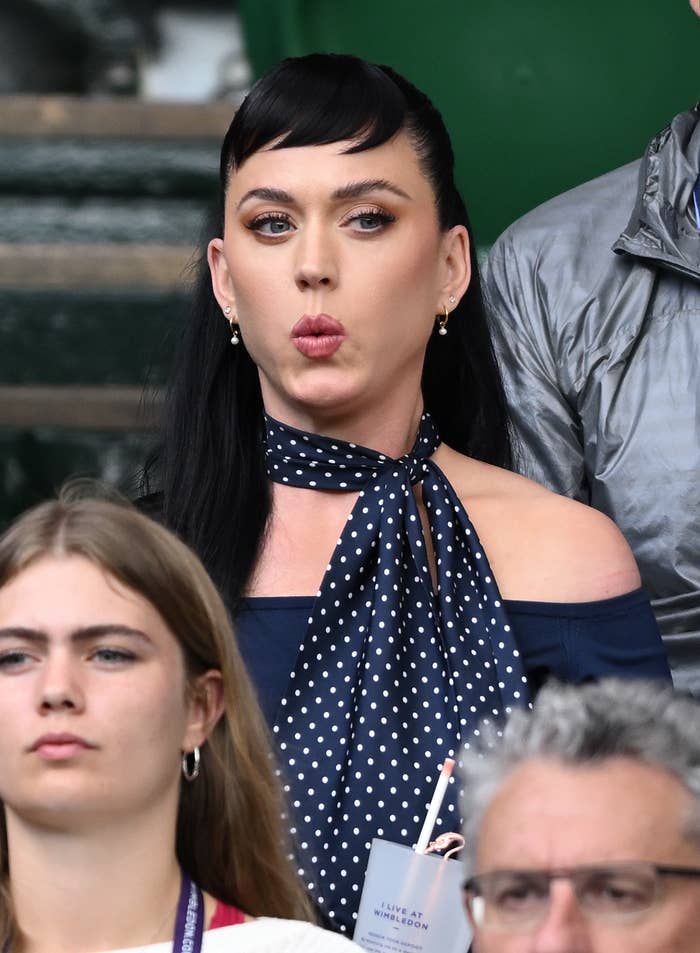 A closeup of Katy Perry reacting to a tennis match from the stands