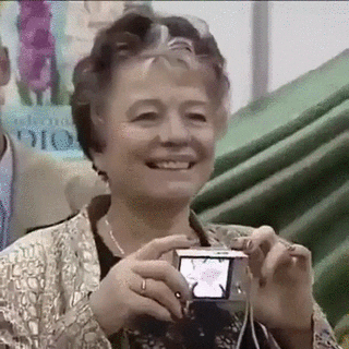 A woman taking a picture with a digital camera but the camera is facing her and flashing