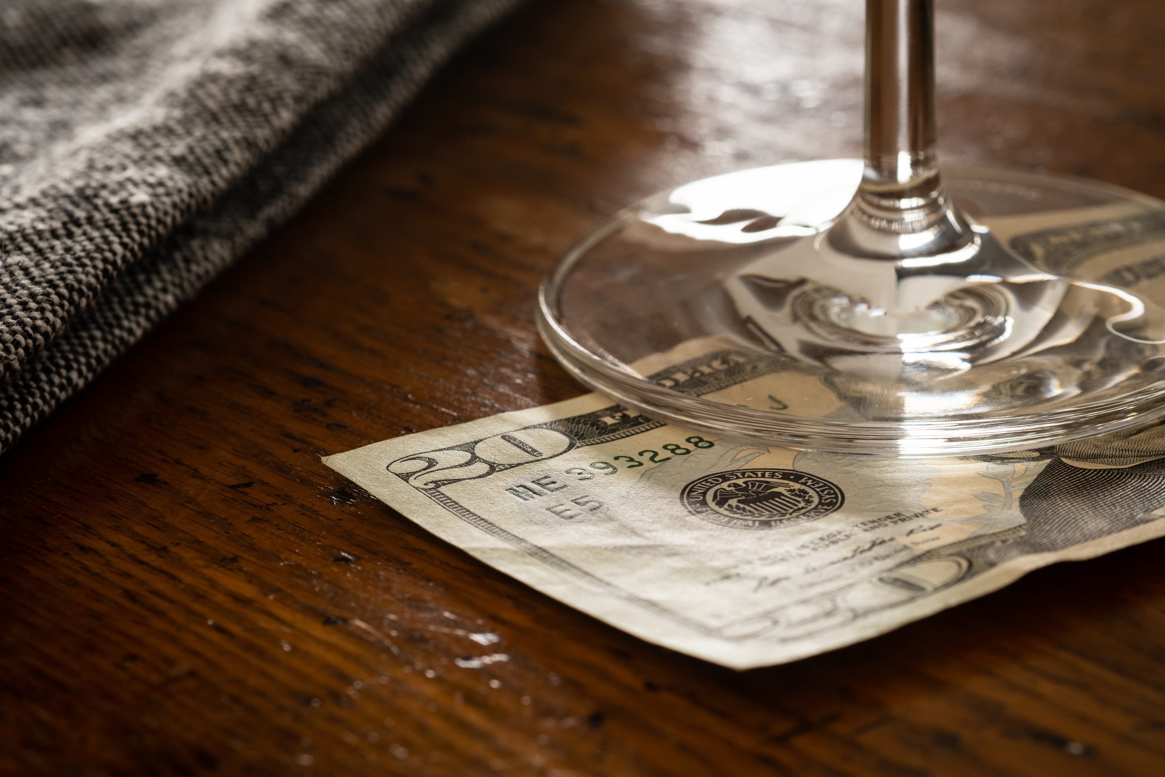 A $20 bill placed under a wine glass