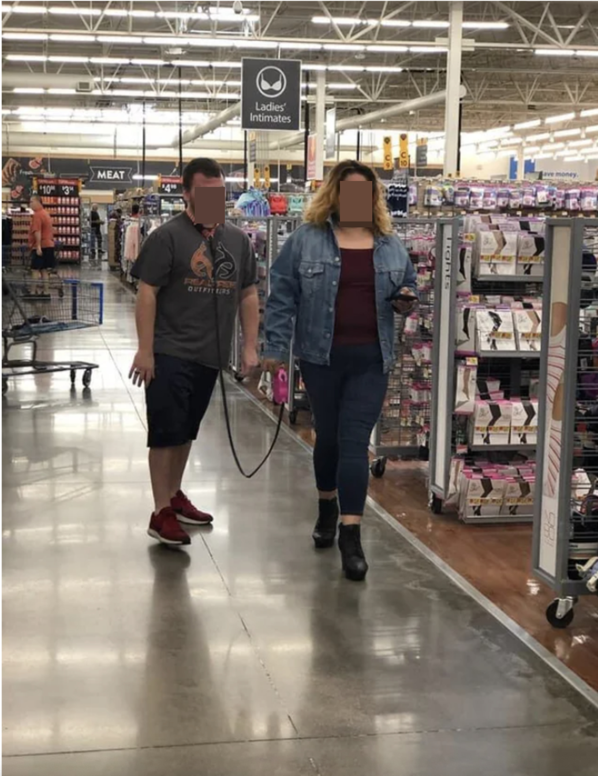 A couple at a grocery store, where the woman is pulling the man behind her on a leash