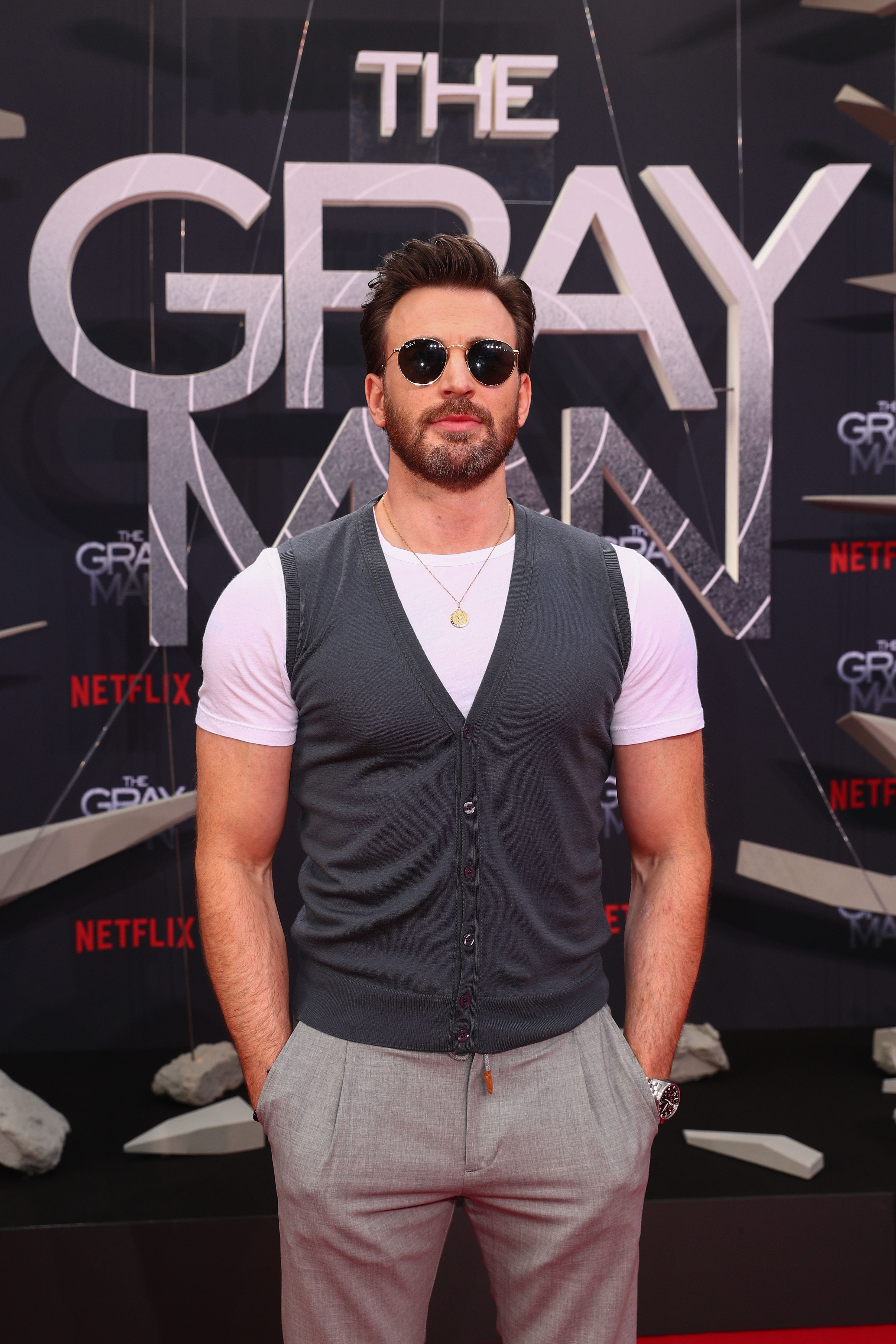 Closeup of Chris Evans at a movie premiere in a t-shirt, sweater vest, and slacks