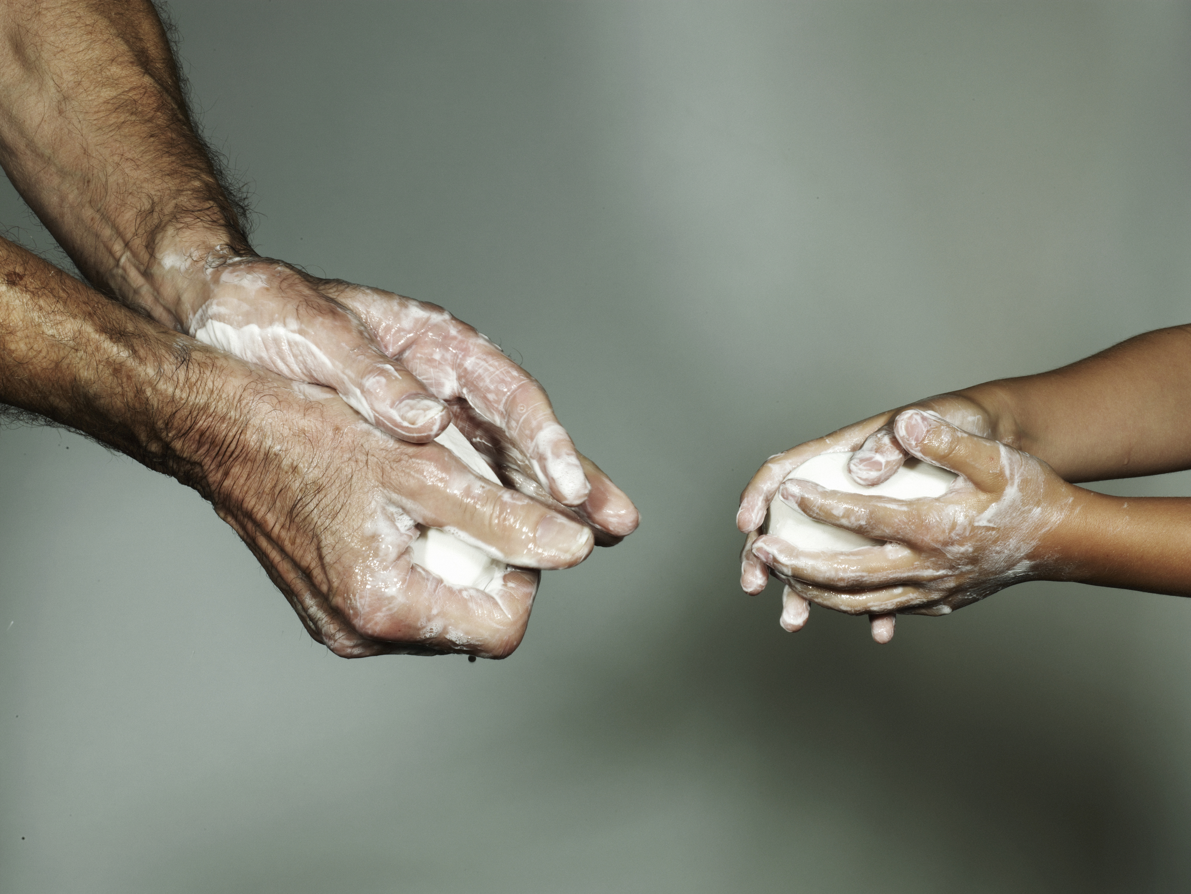 two pairs of hands using soap