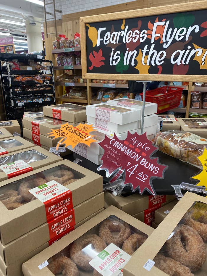 a product stand in trader joe&#x27;s featuring apple cinnamon buns and apple cider donuts