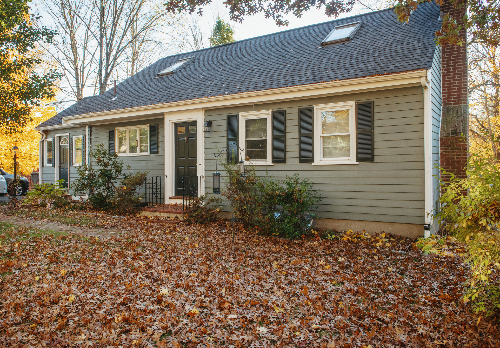 A cute, small home with a yard full of autumn leaves