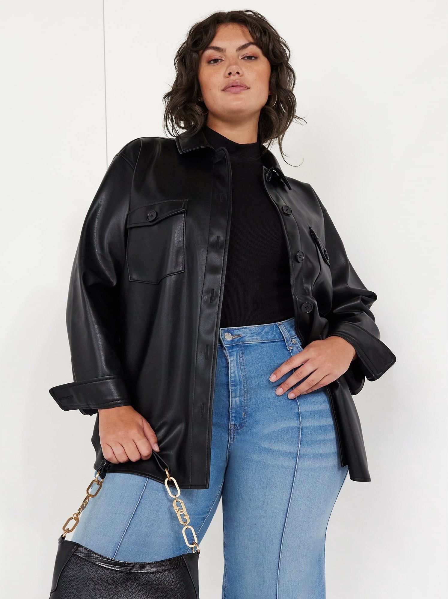 Model wearing a black pleather jacket, jeans, and black purse.