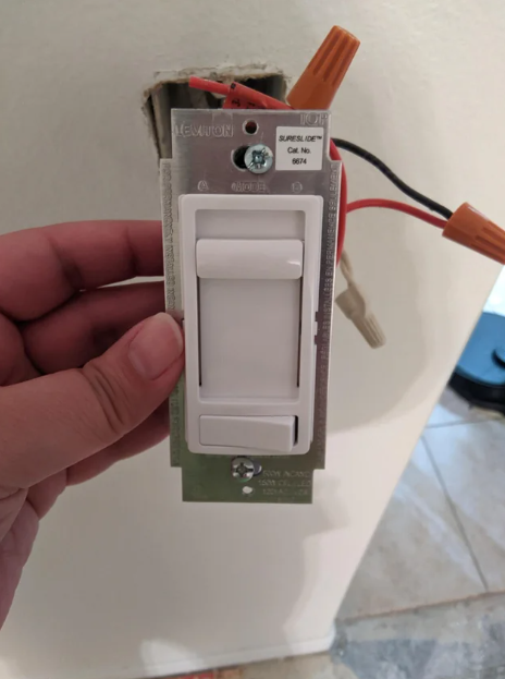 person holding up a dimmer switch