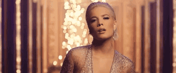 Halsey looks at the camera as fire rises behind her.