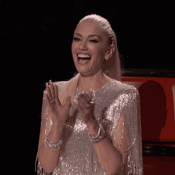 Gwen Stefani claps enthusiastically in a red chair.