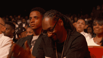 Snoop Dogg smiles and nods with his hands in "Amen" at an award show.