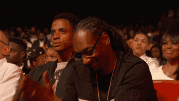 Snoop Dogg smiles and nods with his hands in &quot;Amen&quot; at an award show.