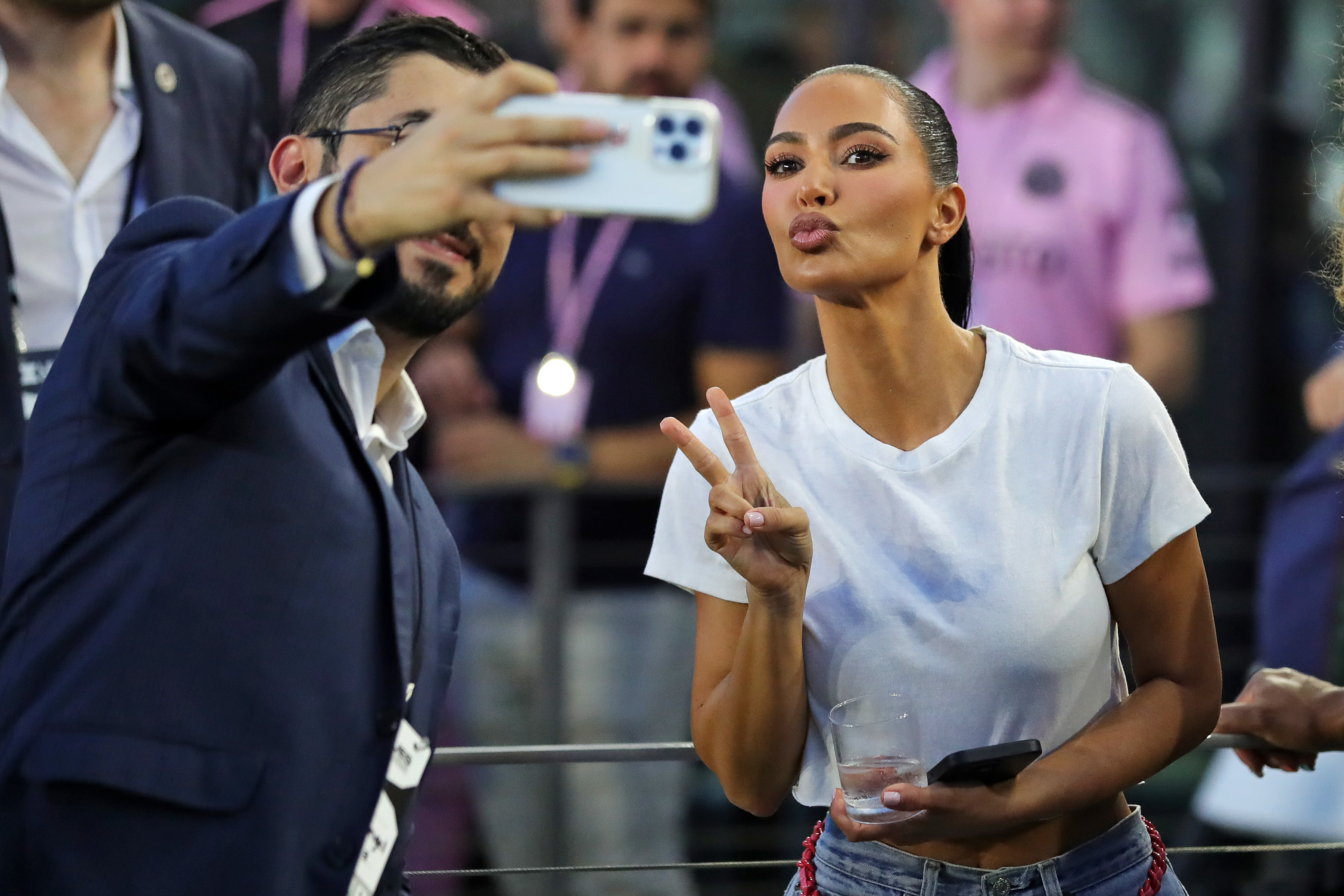 Kim Kardashian gives the peace sign and pouts as she takes a picture with a fan
