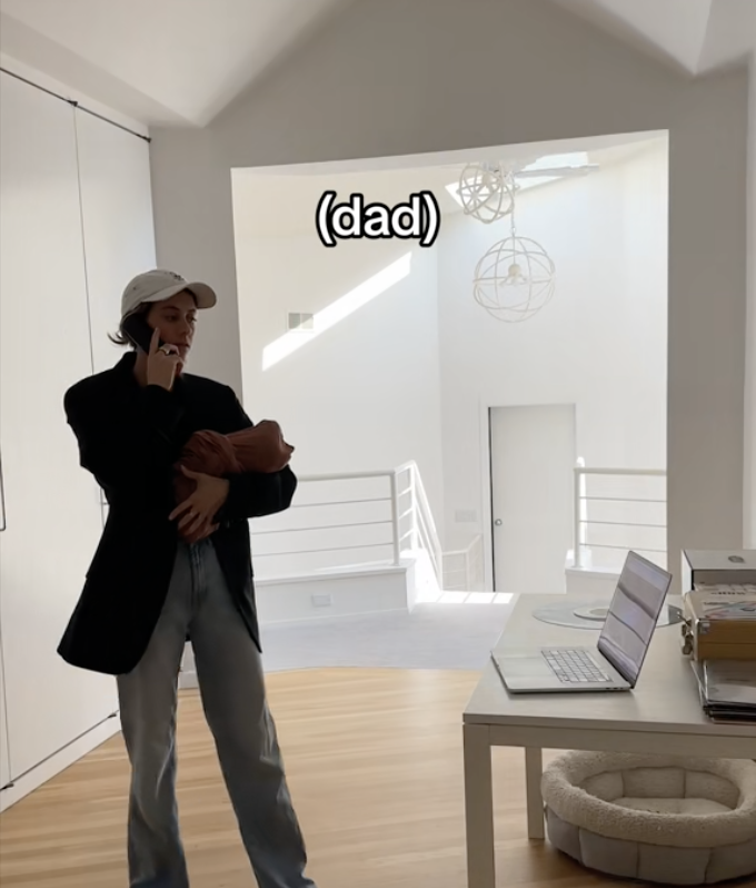 Dad on the phone carrying a baby with a laptop on a desk with caption &quot;dad&quot;