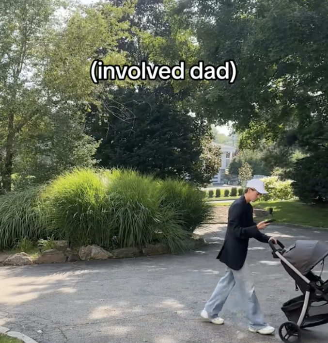 Dad on the phone pushing a baby carriage and checking his phone with &quot;involved dad&quot; caption