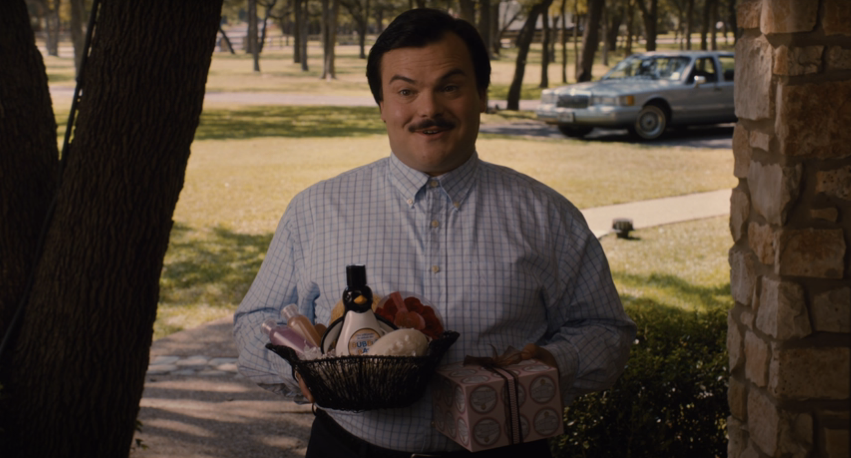 his character holding a gift basket wearing a button down and hair combed down and a mustache
