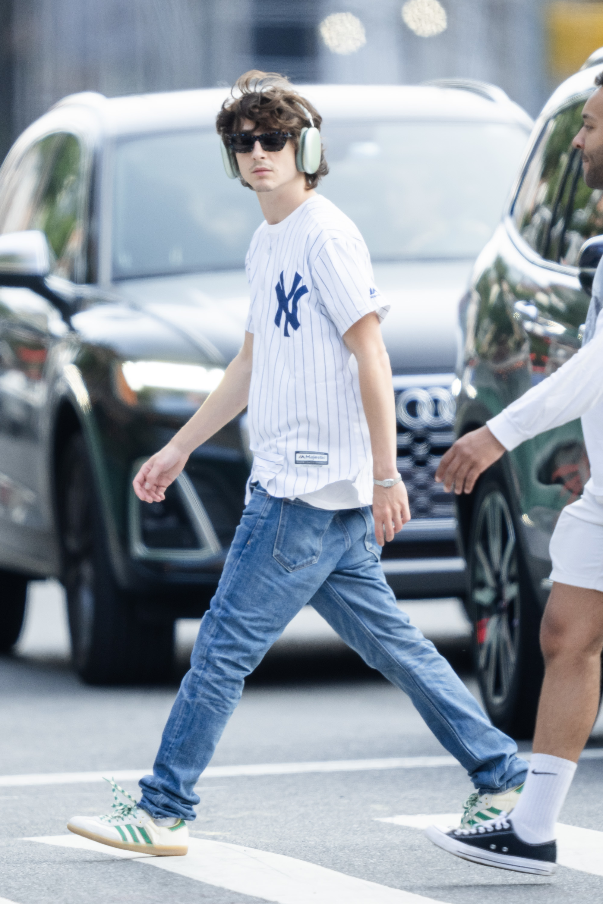 Timothée in jeans and a NY Yankees T-shirt and headphones walking along the street