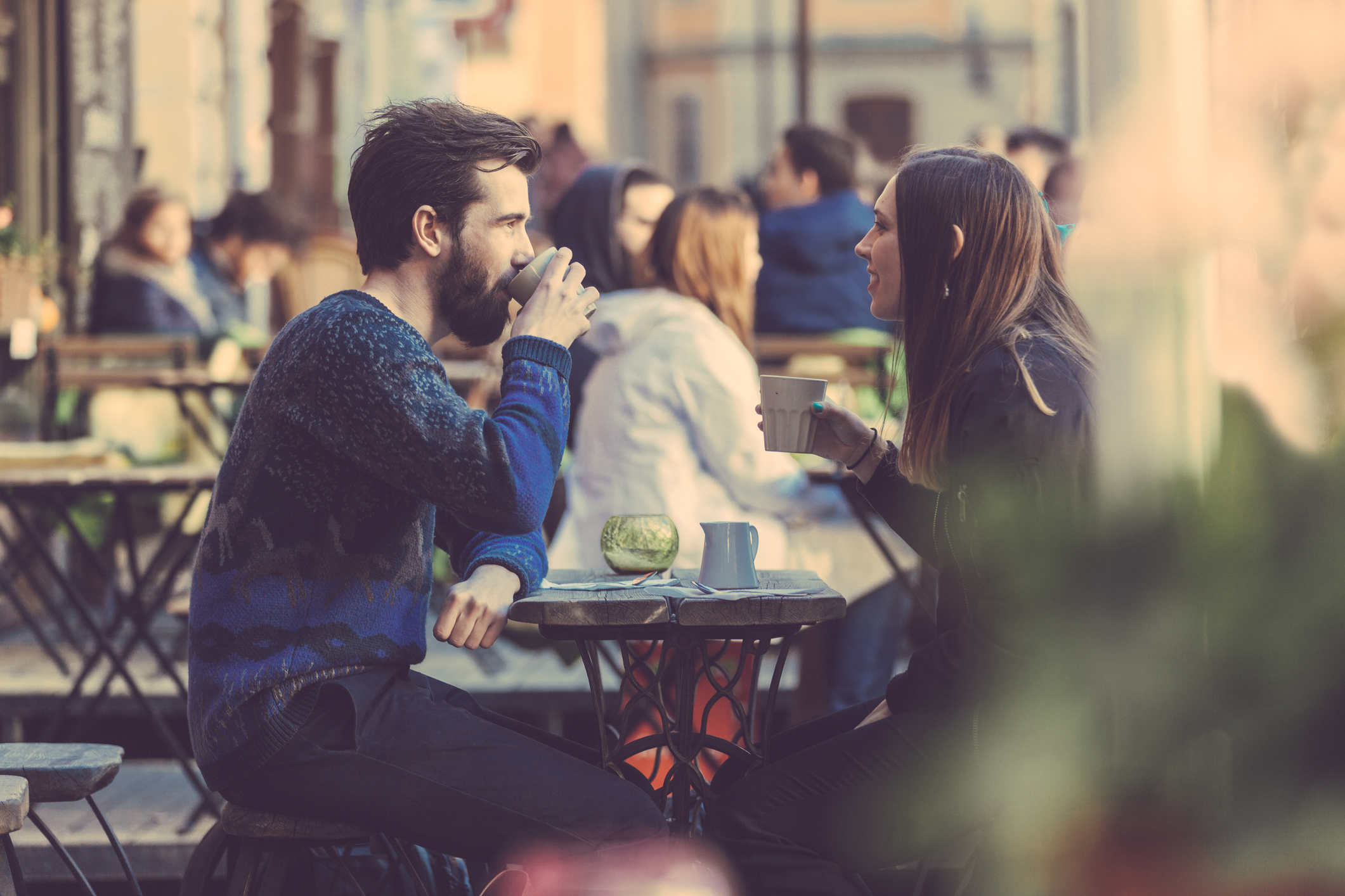 two people drinking coffee outside at a cafe