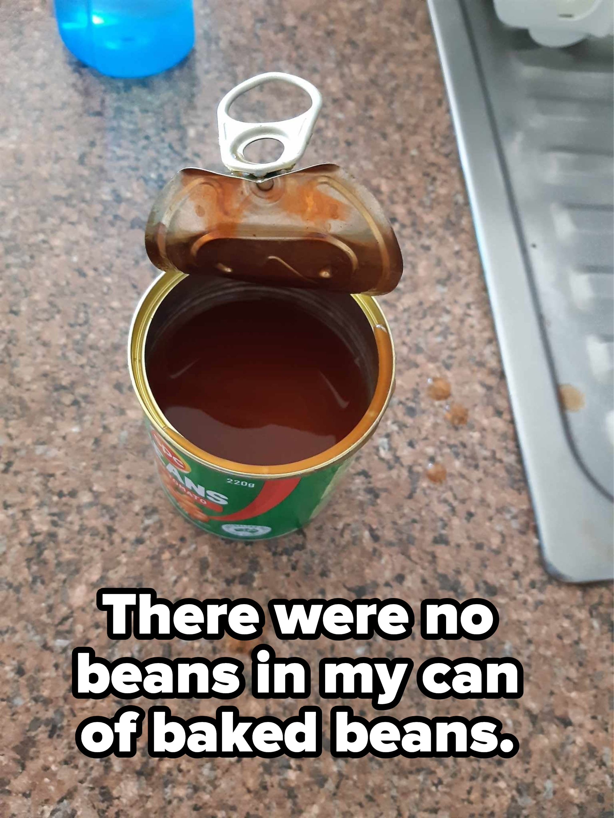 Overhead view of an open can with liquid in it, with caption &quot;There were no beans in my can of baked beans&quot;