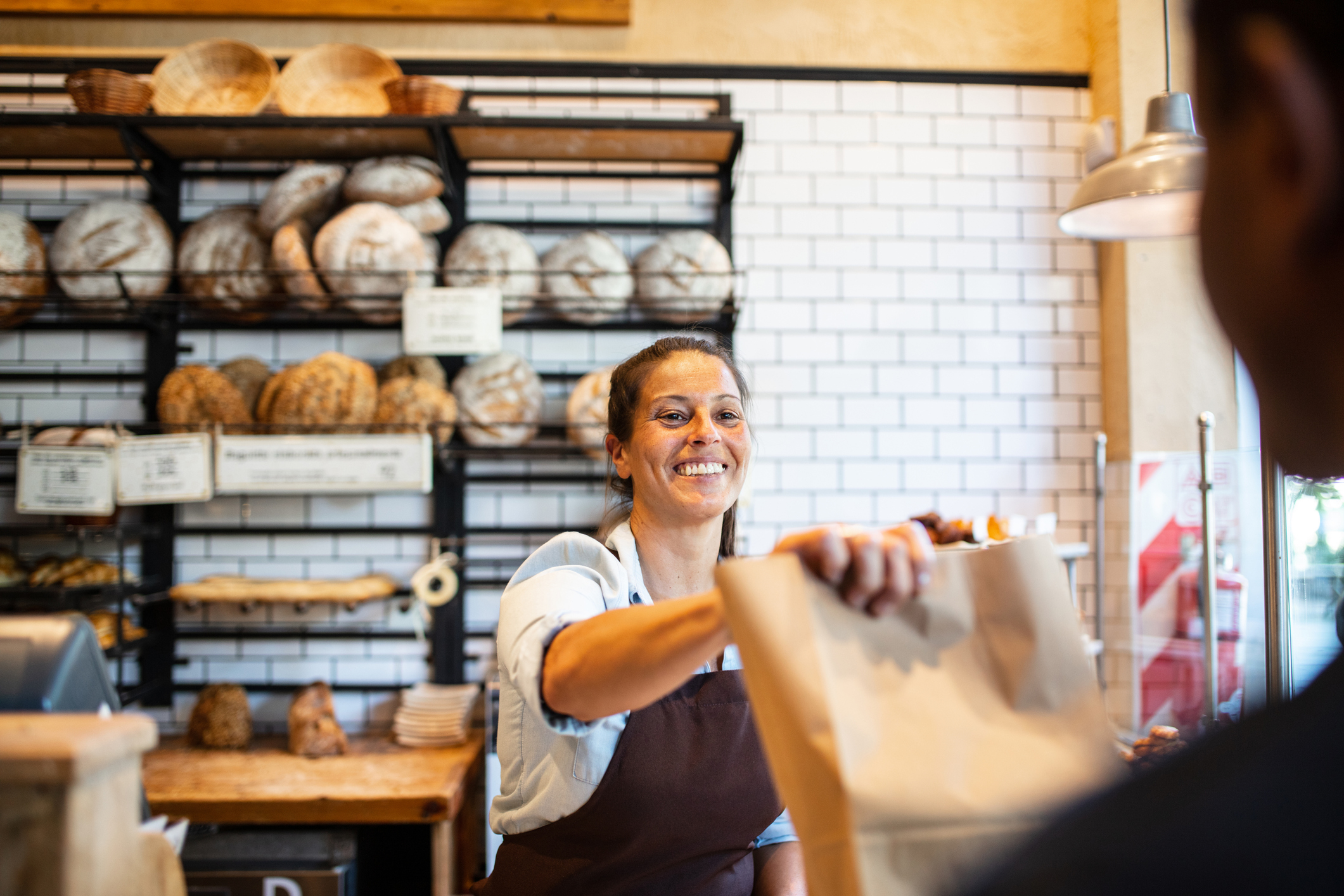 a bakery worker handing a bag to a customer
