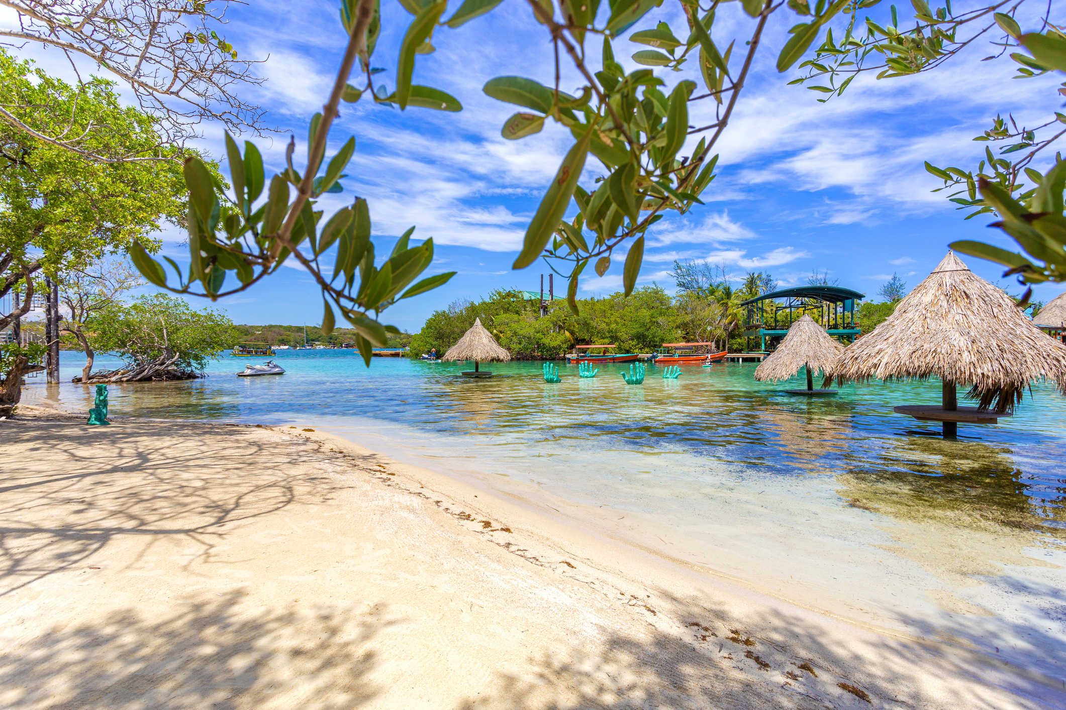 picnic tables in the water shaded with straw umbrellas