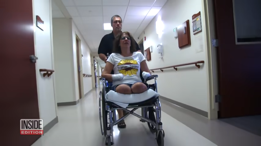 The woman being pushed in a wheelchair in a hospital hallway