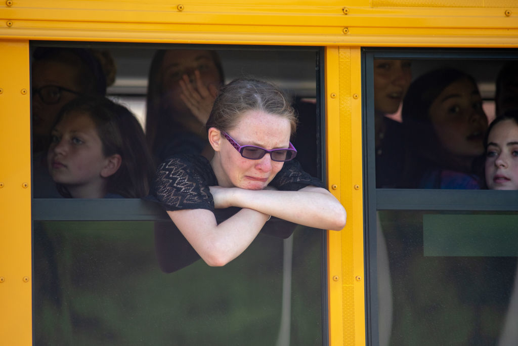 A crying student leaning out of a school bus window
