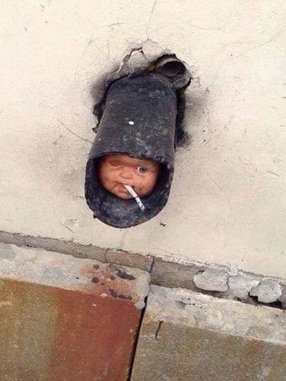 A doll face with a cigarette in a drainpipe