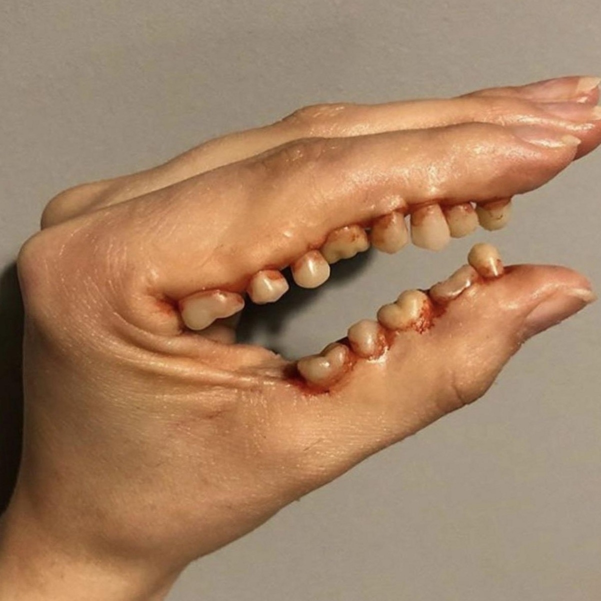 A hand with teeth glued to it