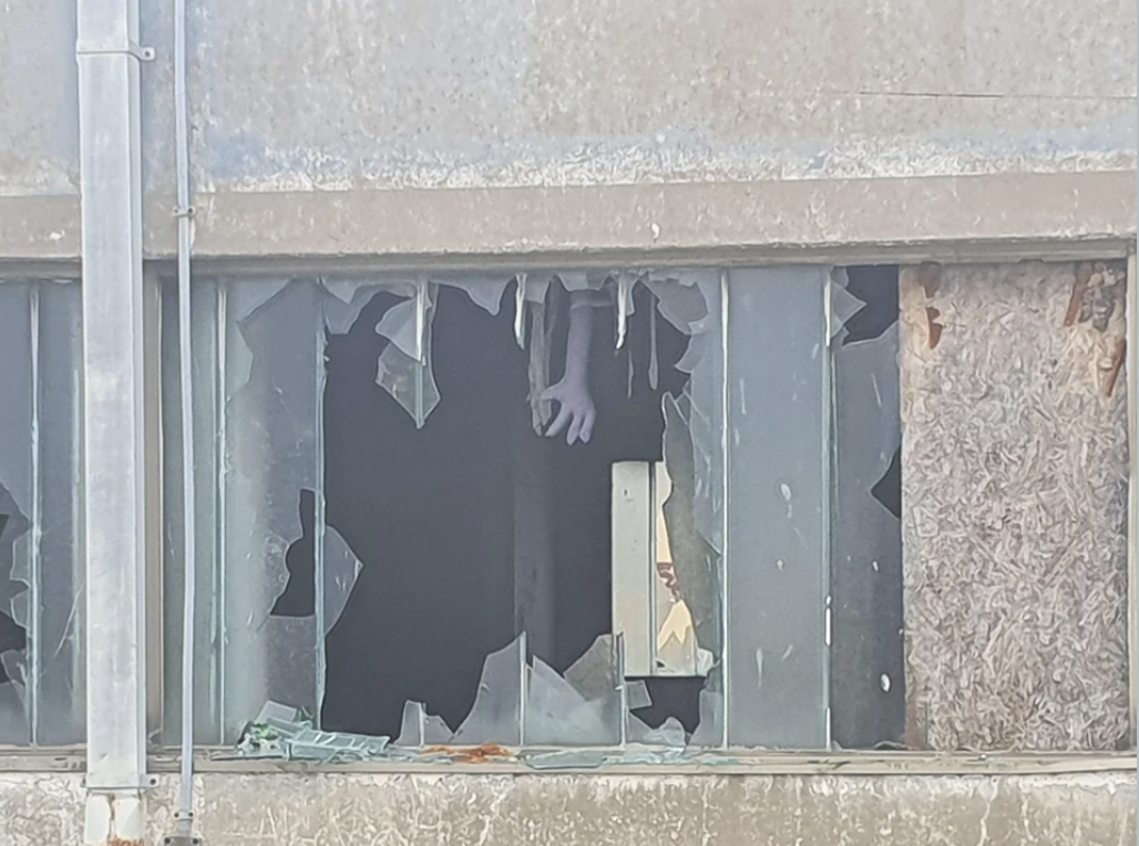 a broke window with a hand visible