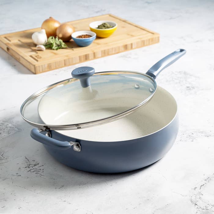 Blue sauté pan with lid on a marble counter.