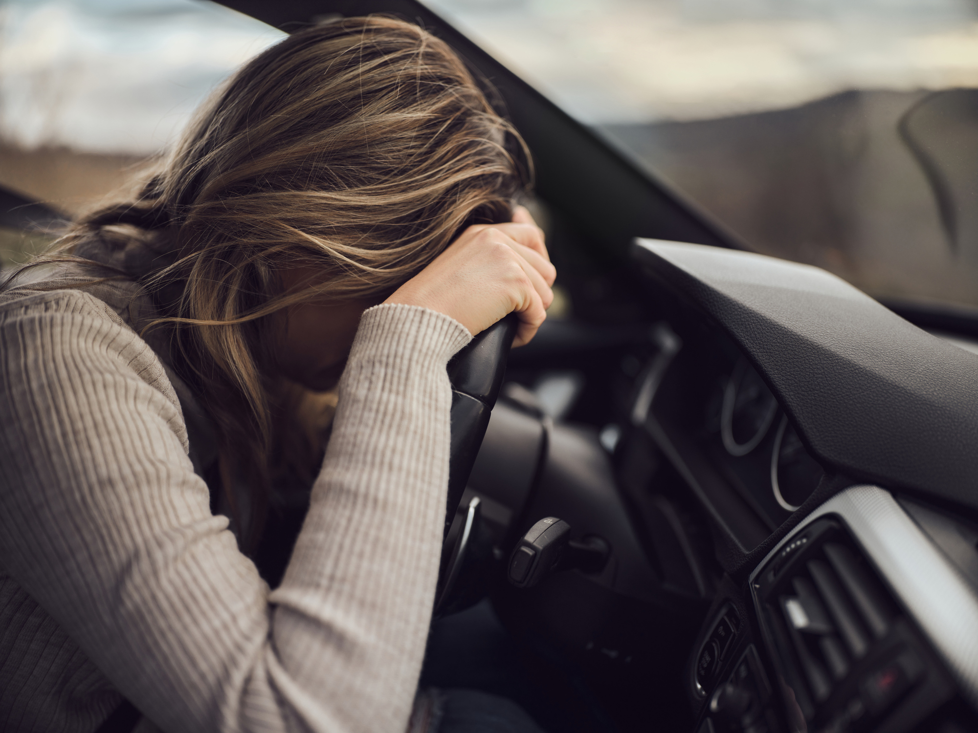 woman with her head on the steering wheel
