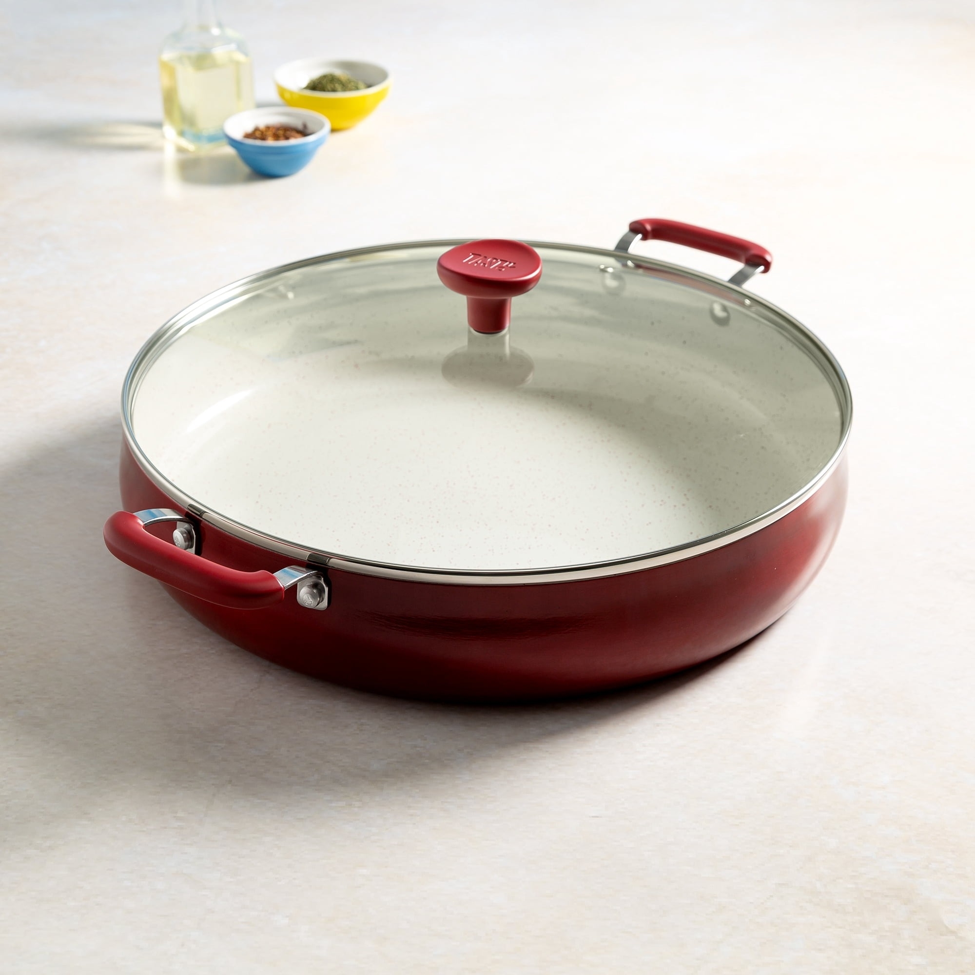 A red sauté pan with a lid and white interior.