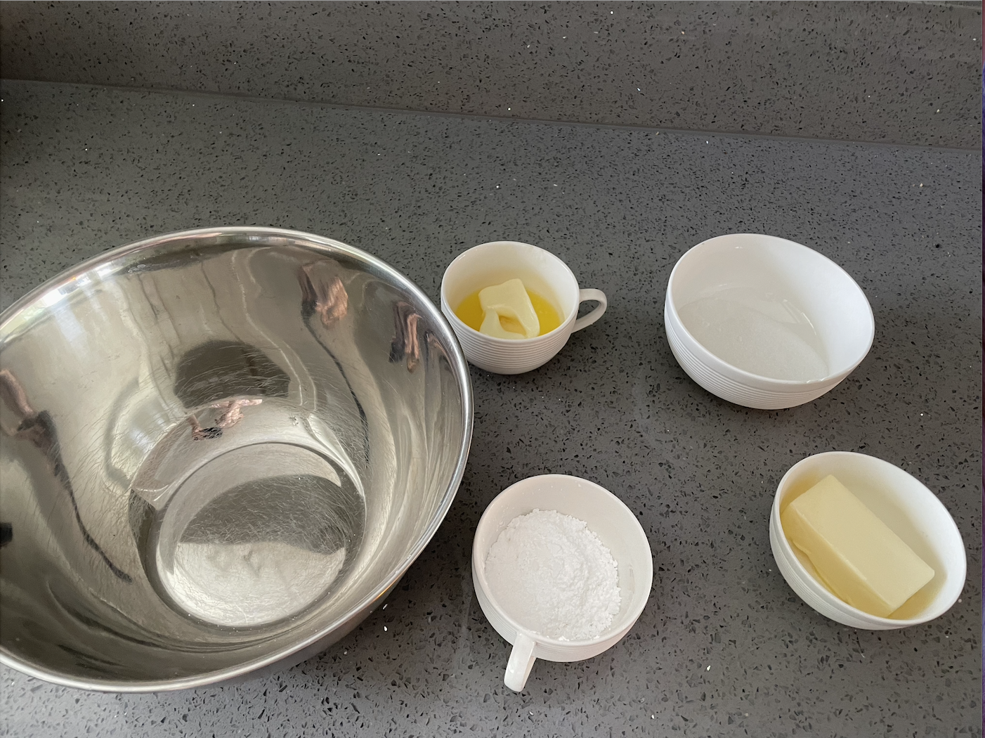An empty bowl, two small bowls of butter, and two bowls of sugar