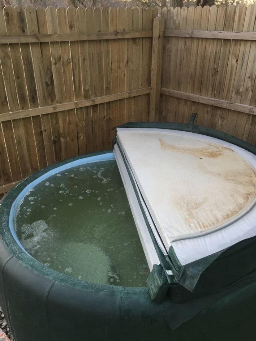 A hot tub with dirty water in it and a rust-colored top