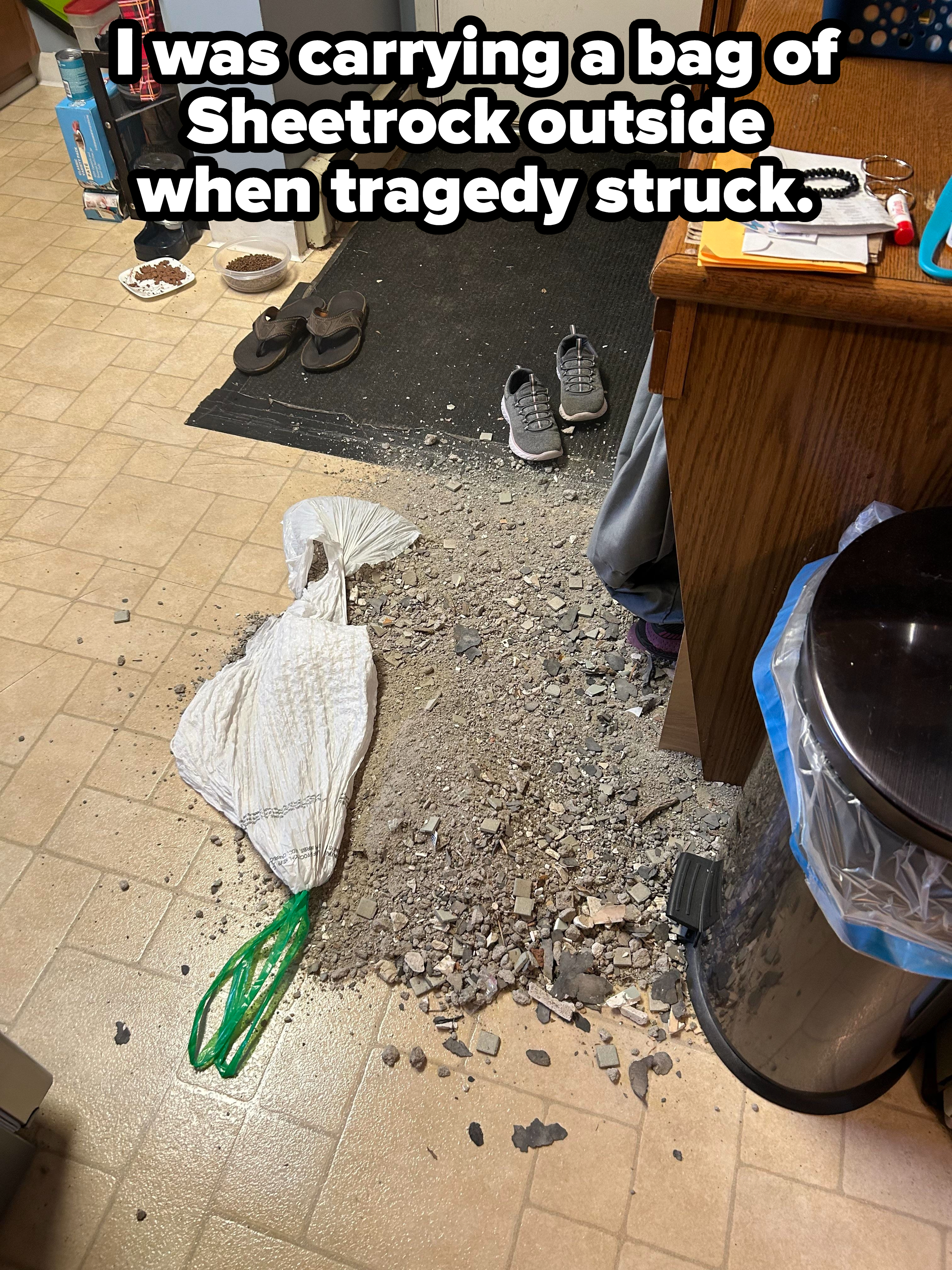 A torn bag with dirt, debris, and drywall scattered all over a kitchen floor, with caption &quot;I was carrying a bag of Sheetrock outside when tragedy struck&quot;