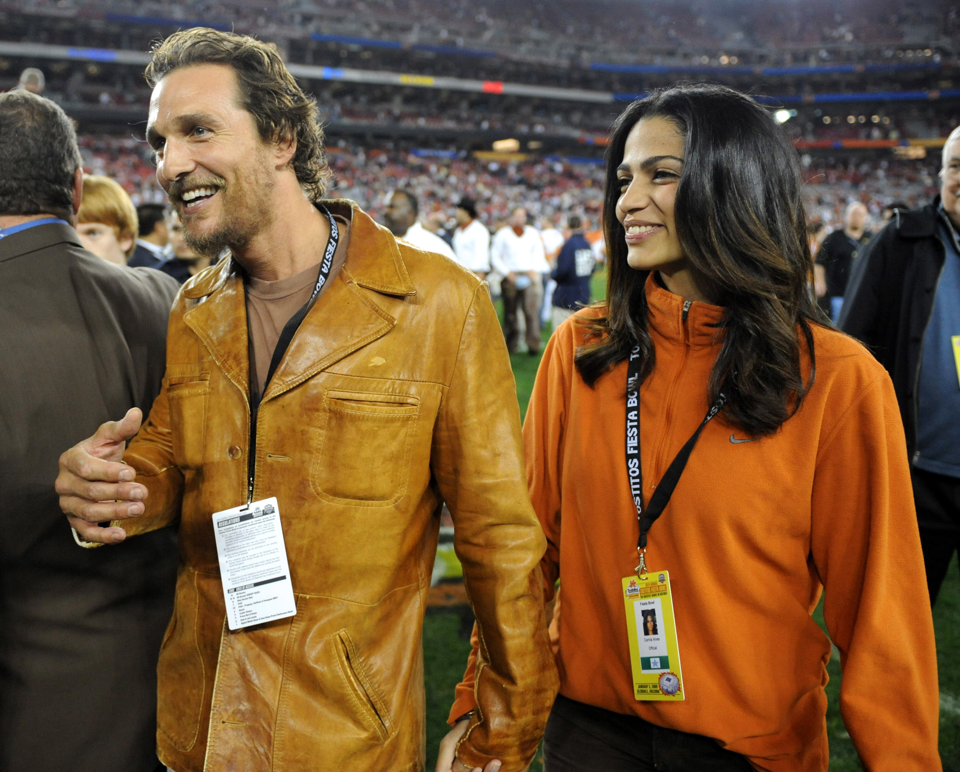 Close-up of Camila and Matthew smiling and holding hands at a sports event