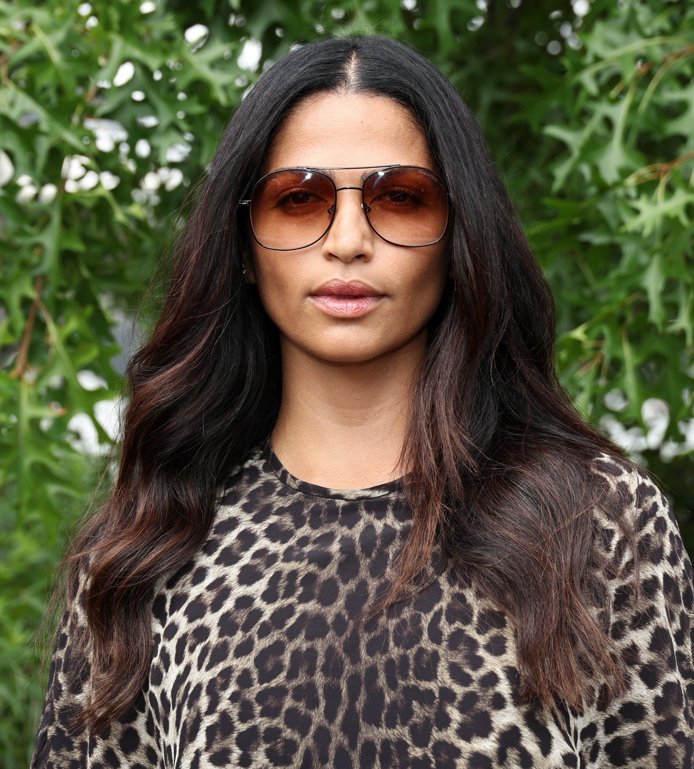 Close-up of Camila in an animal-print top against a leafy backdrop