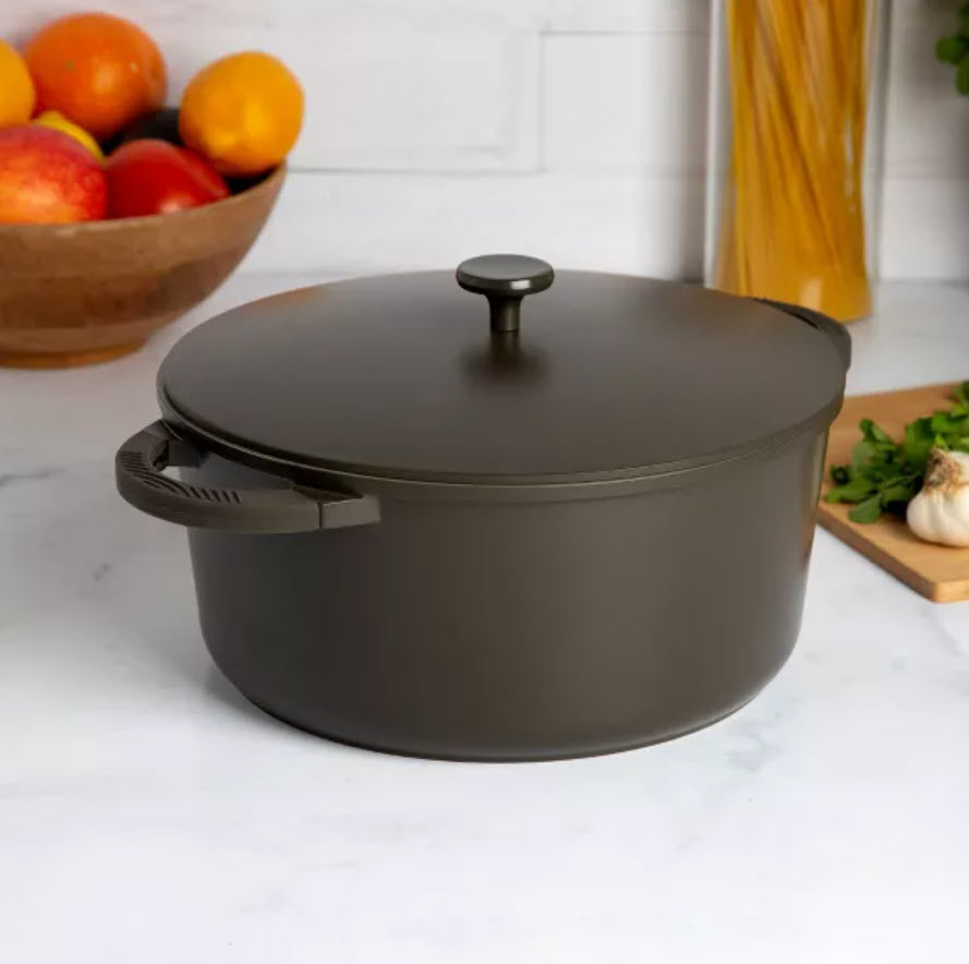 charcoal stockpot with lid sitting on counter next to vegetables and fruit
