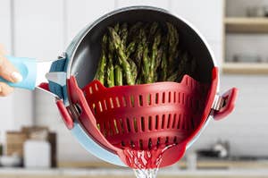 Model straining asparagus in a blue pot.