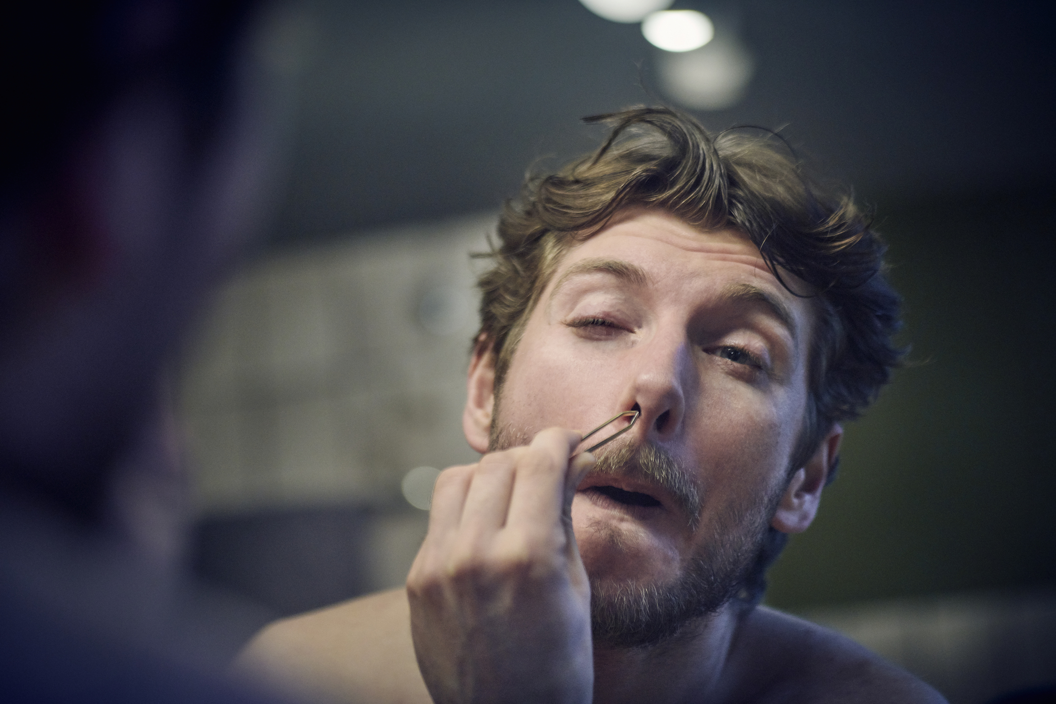 A man is plucking at his nose hairs