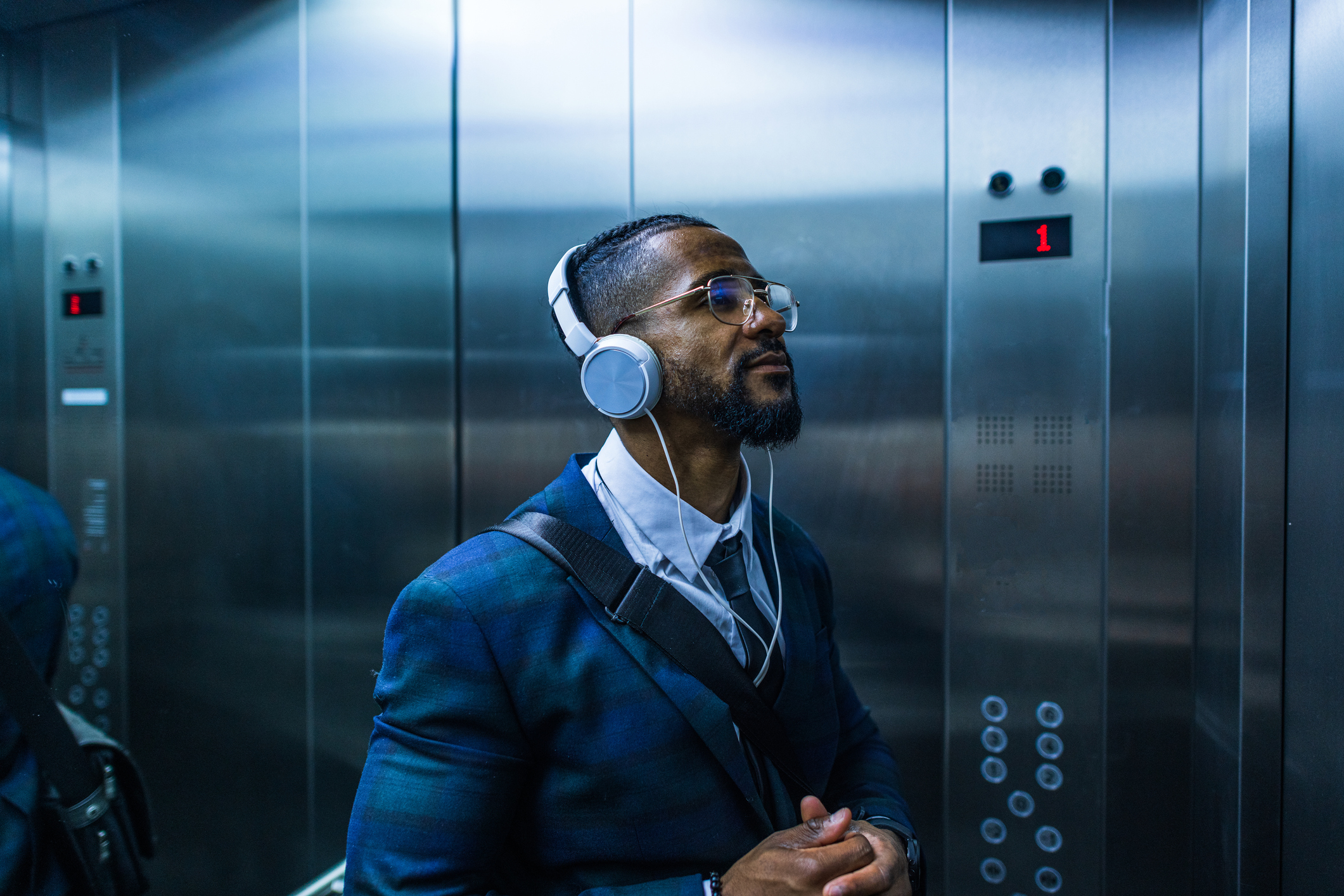 A man is listening to his headphones inside of an elevator