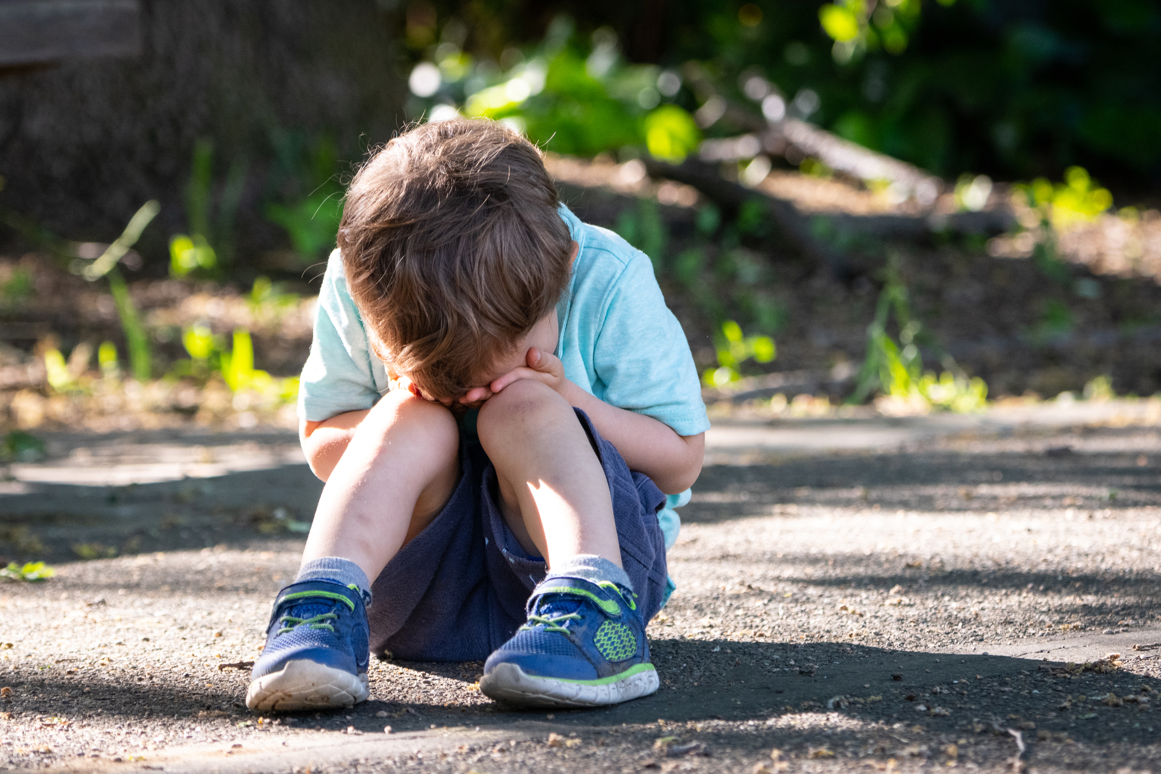 a crying child sitting on the sidewalk