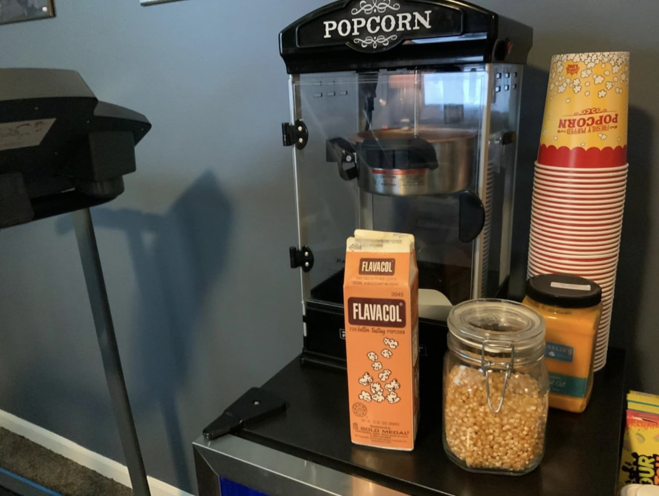 popcorn machine, seasoning, and cups on counter