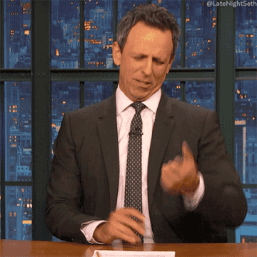 Seth Meyers behind a desk counts his fingers quickly.