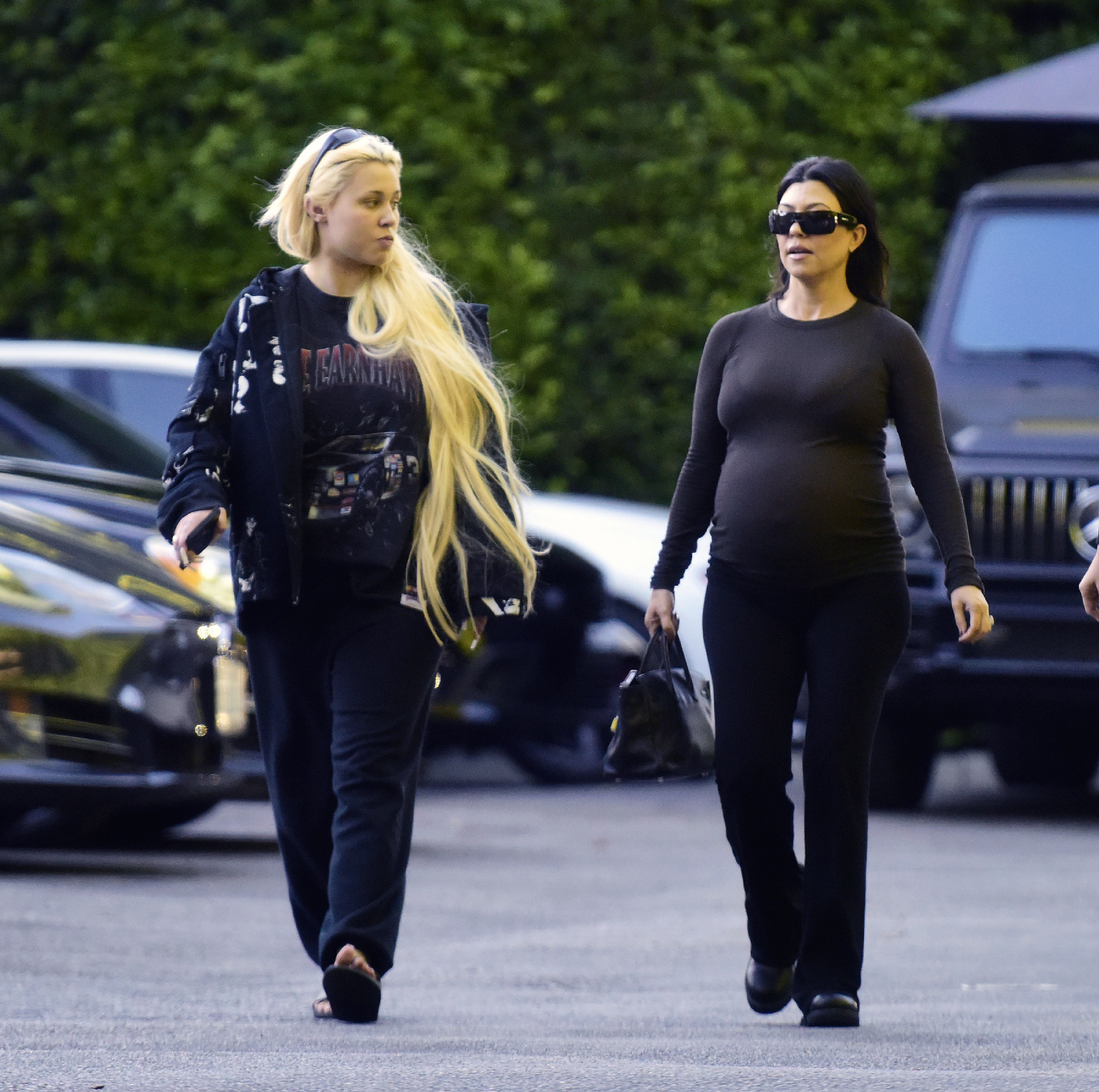 Alabama Barker and a pregnant Kourtney Kardashian walking in a parking lot