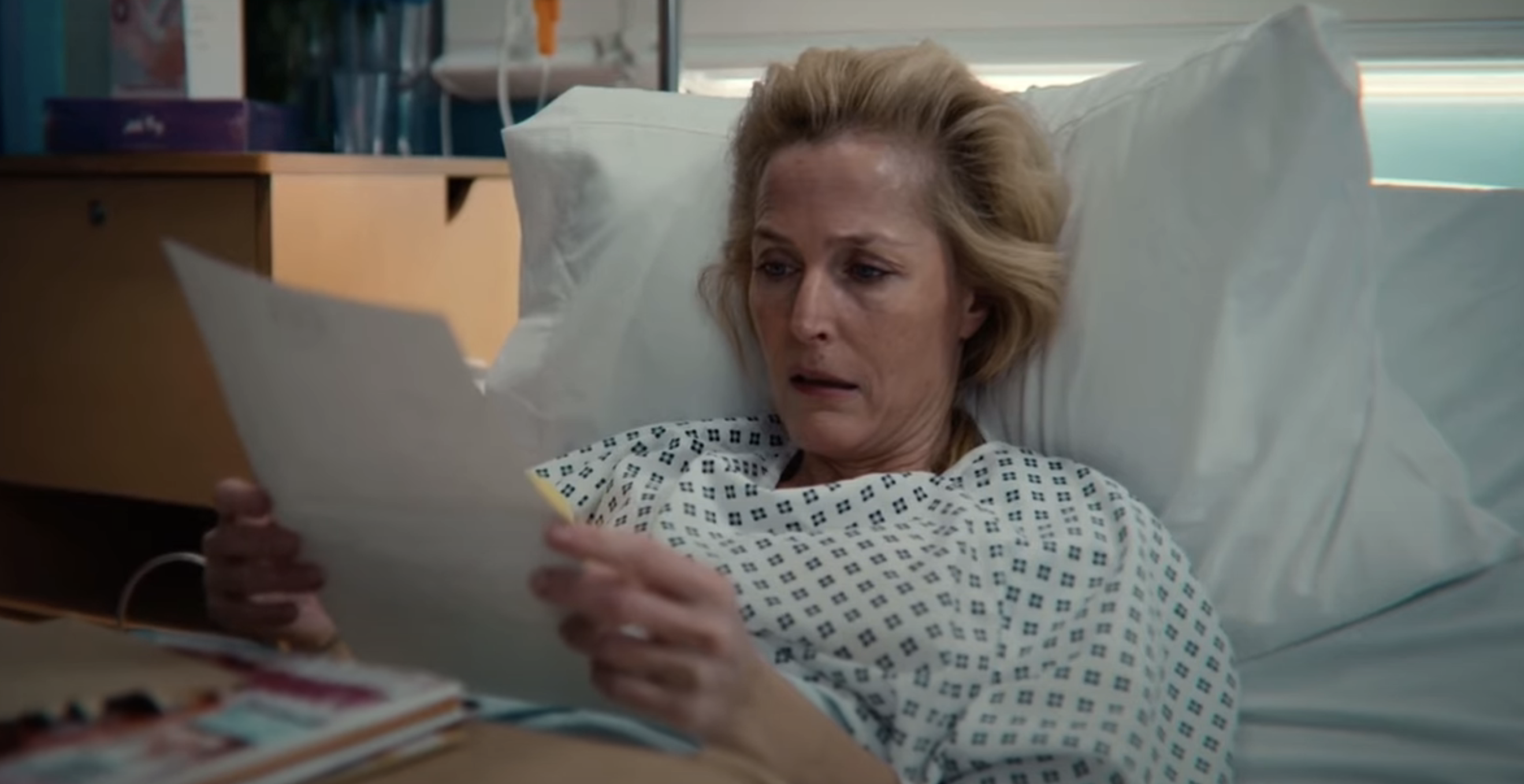 A woman in a hospital bed reading a piece of paper